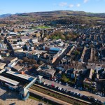 Aerial view of Neath town centre with the railway station and car parks in the foreground and hills behind