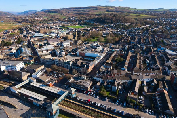 Aerial view of Neath town centre with the railway station and car parks in the foreground and hills behind