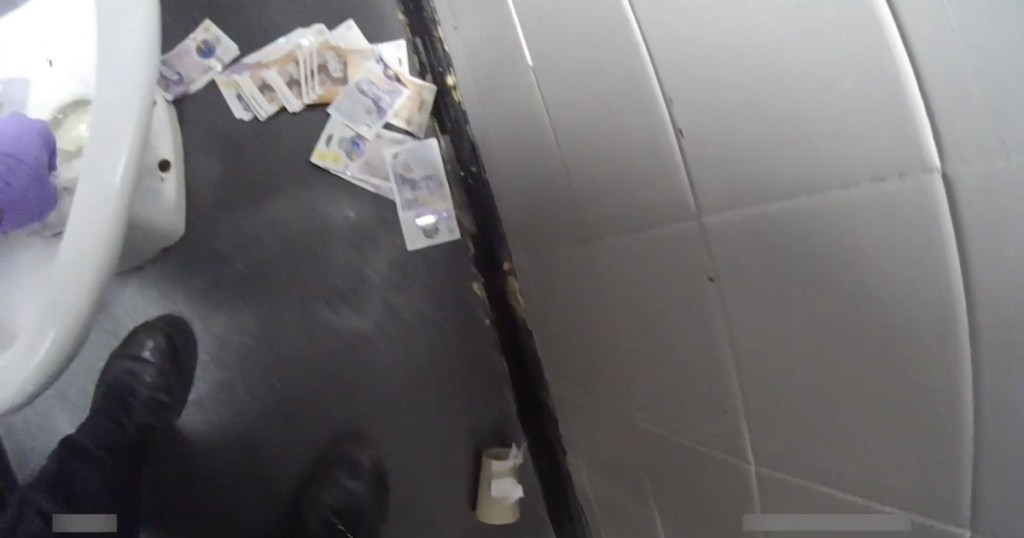 Bodycam footage of banknotes scattered on a bathroom floor during a police search