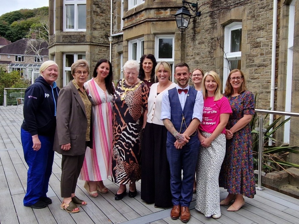 Ten people, including the Lord Mayor wearing her chain of office, standing on a decked terrace outside the Mansion House