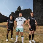 Three Ospreys players in the new 2026/27 kits, two in the black home shirt and one in the white and teal away shirt, at a ruined castle