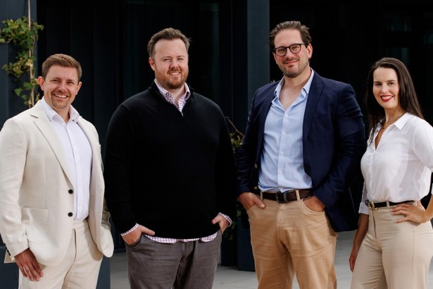 The four members of Ouma's senior leadership team standing outside a dark-clad office building