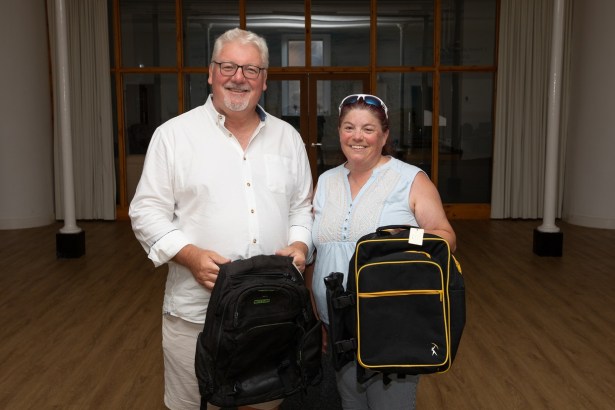 Peter Lynn and Paula Stockley standing in a hall each holding a black rucksack