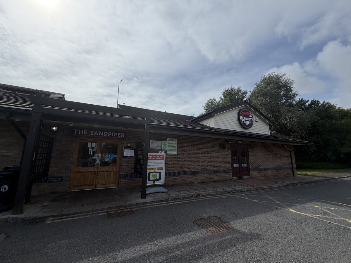 The Sandpiper Brewers Fayre at Sandy Water Park in Llanelli with its entrance doors closed and the menu display case beside them empty