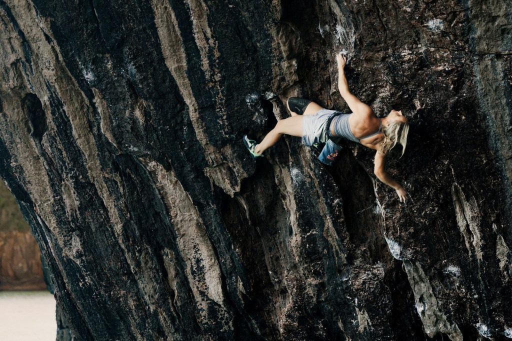 Shauna Coxsey stretched across the dark streaked rock of The Olympiad mid-move