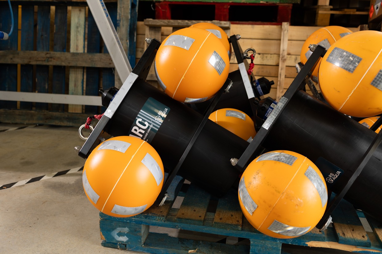Black cylindrical acoustic recorders with orange buoyancy floats stacked on a blue pallet
