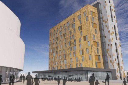 Artist's impression of a gold-clad hotel tower with a rooftop bar beside the white curved wall of Swansea Arena, with people walking in the square below