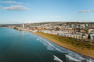 Aerial view of Swansea Bay beach with waves breaking on the sand, seafront apartments and Meridian Tower behind