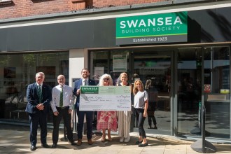 Six people holding a giant £10,000 cheque made out to Prostate Cymru outside the Swansea Building Society branch in Swansea