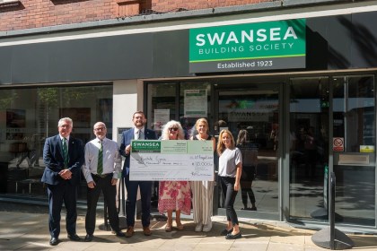 Six people holding a giant £10,000 cheque made out to Prostate Cymru outside the Swansea Building Society branch in Swansea