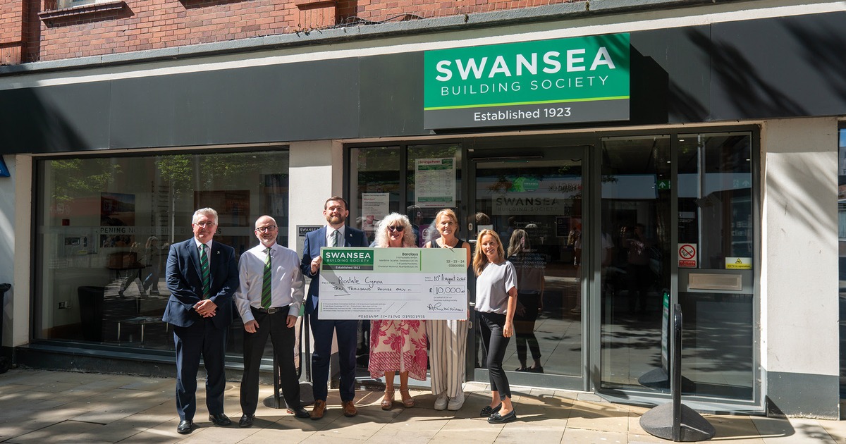 Six people holding a giant £10,000 cheque made out to Prostate Cymru outside the Swansea Building Society branch in Swansea