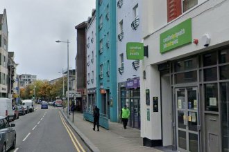 The Jobcentre Plus on Swansea High Street, with its bilingual green canolfan byd gwaith sign above the entrance