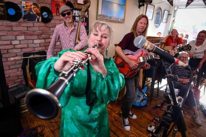 A clarinettist in a green dress performs at a packed free gig during Swansea International Jazz Festival, with a double bassist and guitarists behind her