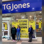 Three shop staff standing in front of the TGJones store in Bridgend's Rhiw Shopping Centre, with yellow 'store closing down, up to 30% off' posters filling the window behind them