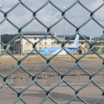 A TUI aircraft on the tarmac at Cardiff Airport seen through the perimeter fence, with the airport's Holiday Inn Express behind