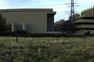 Photomontage showing large windowless data centre buildings and a multi-storey structure rising behind a hedgerow and rough grassland, with an electricity pylon between them