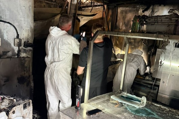 People in white protective suits examining the burnt-out kitchen at Verdi's in Mumbles, with scorched walls, ceiling and steel counters