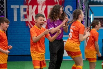 Ysgol Tyle'r Ynn pupils in orange Tekkers kit celebrating alongside presenter Huw Owen on the show's pitch