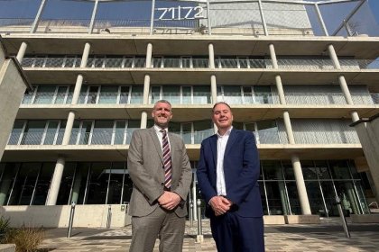 IWG's Mark Potton and council leader Rob Stewart in suits outside the glass and concrete 71/72 Kingsway office building, with the 71/72 sign on its roof