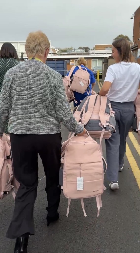 People carrying pink Bailey's Bags backpacks across a car park towards Velindre Cancer Centre