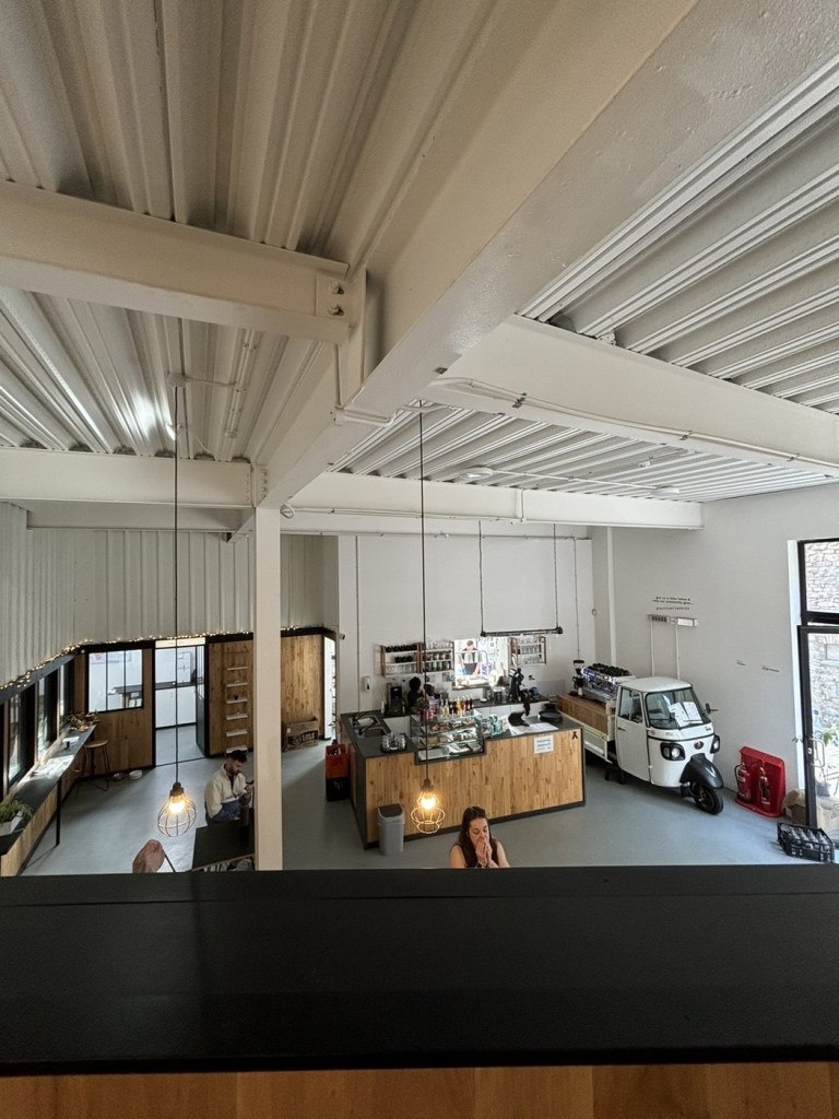 The counter, coffee machine and a parked three-wheeler van inside Basekamp coffee shop at Urban Village, Swansea, seen from the mezzanine