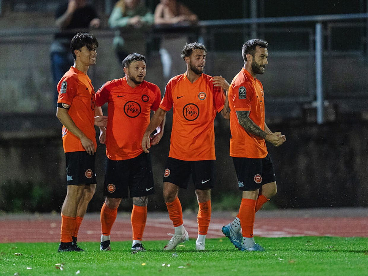 Bradley Gibbings, second from right, celebrating with three Pure Swansea team-mates in orange shirts on the pitch at night