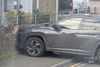 A grey Hyundai SUV with its front against a damaged brick wall and railings on Coity Road, Bridgend