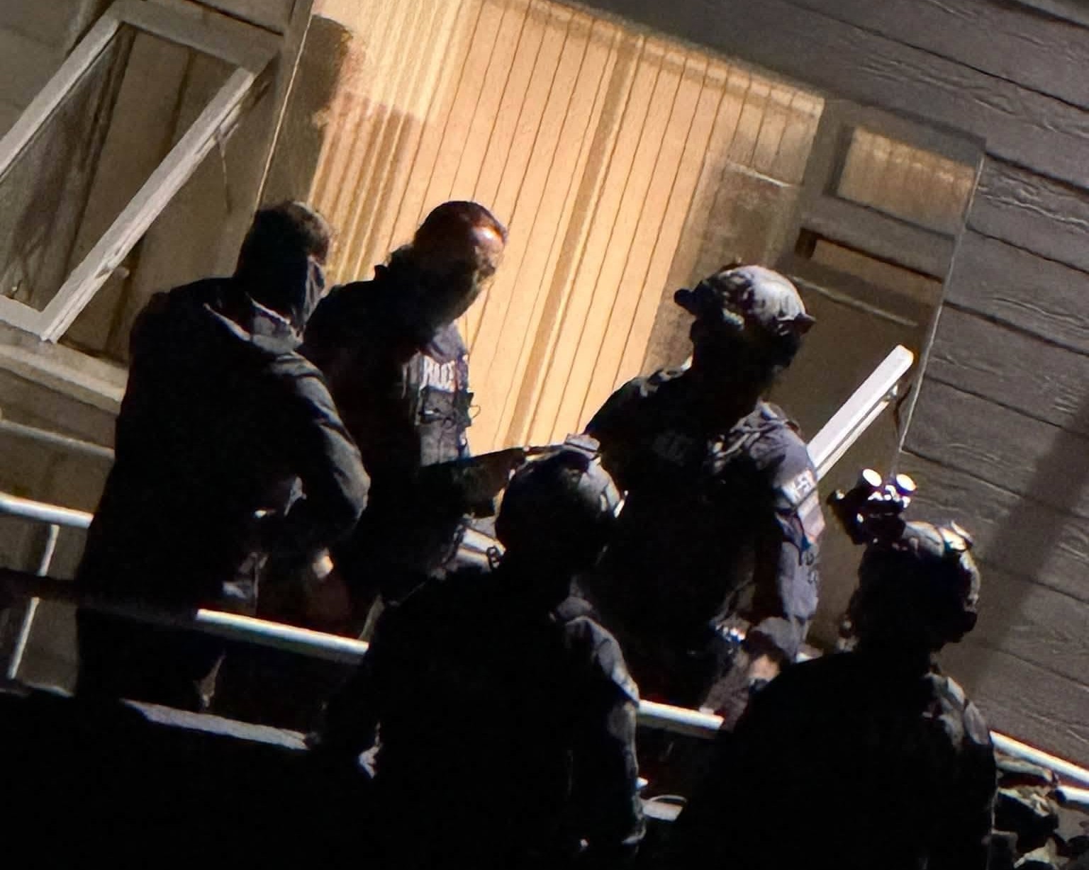 Police officers in helmets and tactical kit at the lit doorway of a building at night during the Bridgend operation