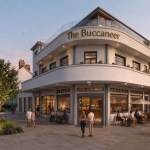 Artist's impression of The Buccaneer as a curved white three-storey building with gold lettering, a glass rooftop terrace and people at café tables outside