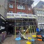 A banner reading Roof off, sound still on hung on scaffolding over the black frontage of The Bunkhouse bar and music venue on the Kingsway, Swansea