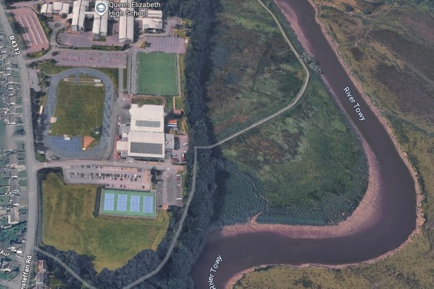 Aerial view of Carmarthen Leisure Centre in Johnstown with the grassed field beside its tennis courts, Llansteffan Road to the left and the River Towy to the right