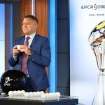 The EPCR Challenge Cup trophy on display beside a man drawing a ball at the Challenge Cup pool draw