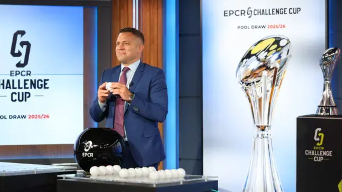 The EPCR Challenge Cup trophy on display beside a man drawing a ball at the Challenge Cup pool draw