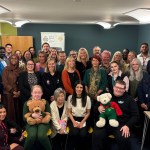 Children's Commissioner for Wales Rocio Cifuentes seated in the front row of a large group of guests at the opening of the new Swansea office
