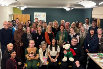 Children's Commissioner for Wales Rocio Cifuentes seated in the front row of a large group of guests at the opening of the new Swansea office