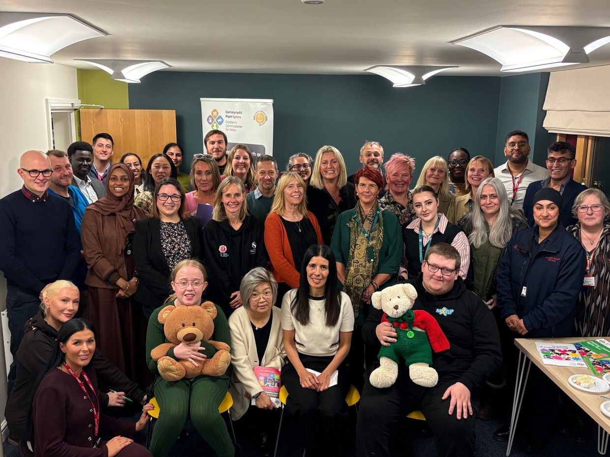 Children's Commissioner for Wales Rocio Cifuentes seated in the front row of a large group of guests at the opening of the new Swansea office
