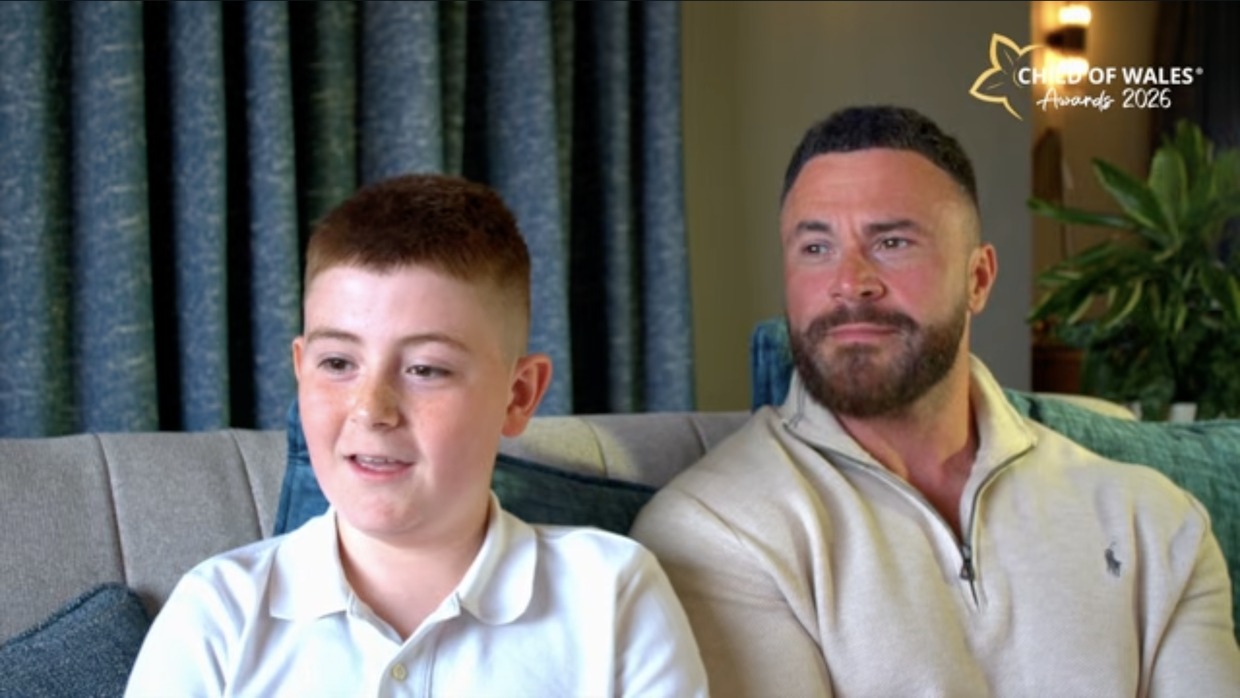Cian Evans sitting on a sofa beside his dad, Alex, at home