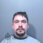 Police custody photograph of Damien Samuel, a man with short dark hair and a goatee beard in a grey top