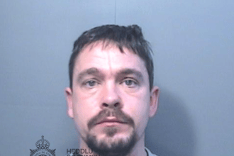 Police custody photograph of Damien Samuel, a man with short dark hair and a goatee beard in a grey top