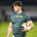 Ospreys fly-half Dan Edwards in a green Ospreys training top with the number 10, holding a rugby ball on the pitch