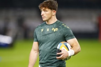Ospreys fly-half Dan Edwards in a green Ospreys training top with the number 10, holding a rugby ball on the pitch