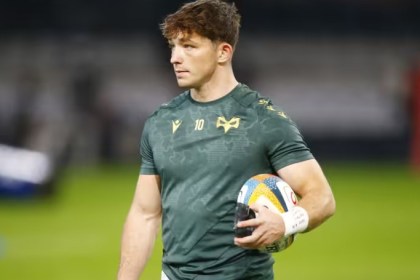 Ospreys fly-half Dan Edwards in a green Ospreys training top with the number 10, holding a rugby ball on the pitch