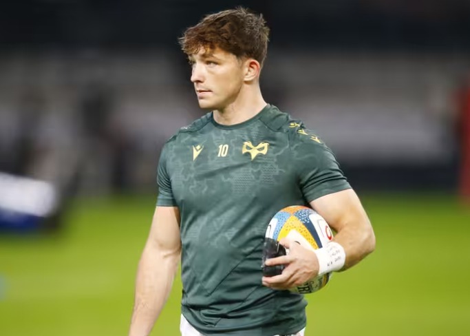 Ospreys fly-half Dan Edwards in a green Ospreys training top with the number 10, holding a rugby ball on the pitch