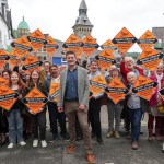 David Chadwick in a checked jacket smiling in front of a crowd of supporters holding orange Welsh Liberal Democrats diamond placards
