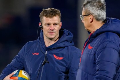 Scarlets head coach Dwayne Peel, holding a ball and wearing a headset, talks with director of rugby Nigel Davies