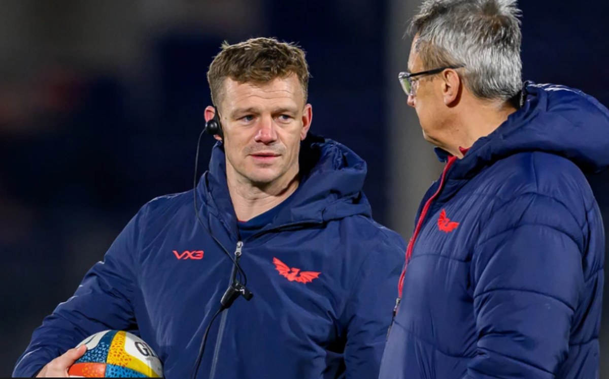 Scarlets head coach Dwayne Peel, holding a ball and wearing a headset, talks with director of rugby Nigel Davies