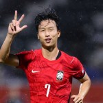 Swansea City winger Eom Ji-sung celebrates in a red South Korea number 7 shirt on a rainy night