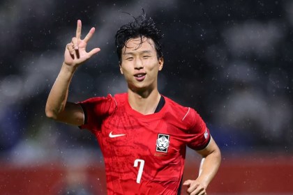 Swansea City winger Eom Ji-sung celebrates in a red South Korea number 7 shirt on a rainy night