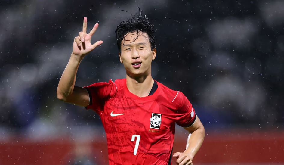 Swansea City winger Eom Ji-sung celebrates in a red South Korea number 7 shirt on a rainy night