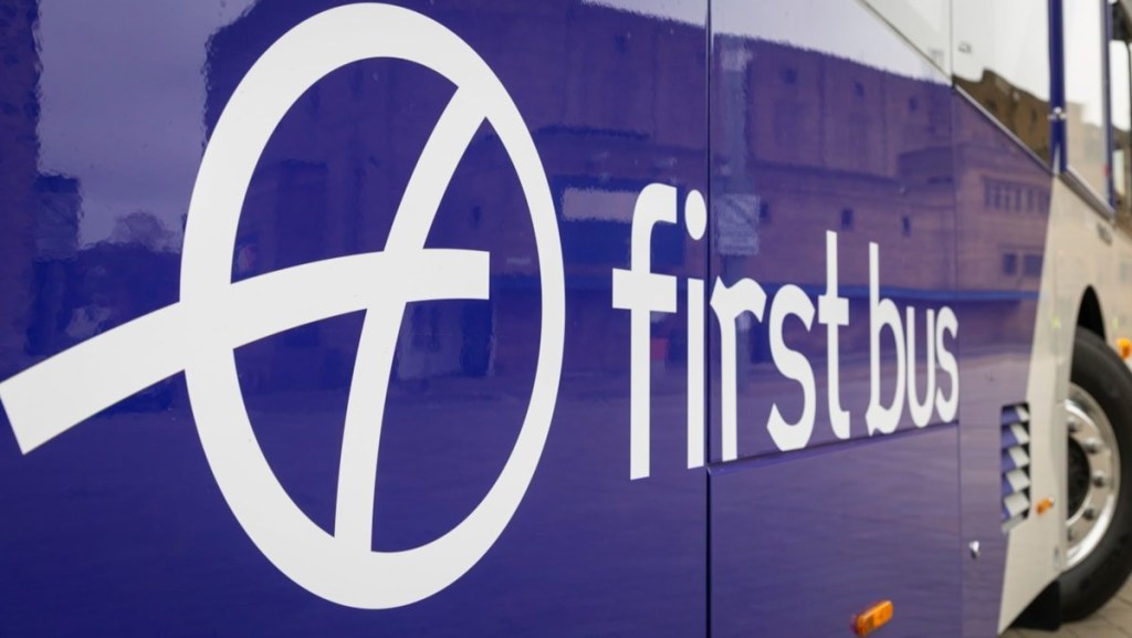Close-up of the white First Bus logo and wordmark on the purple side panel of a bus